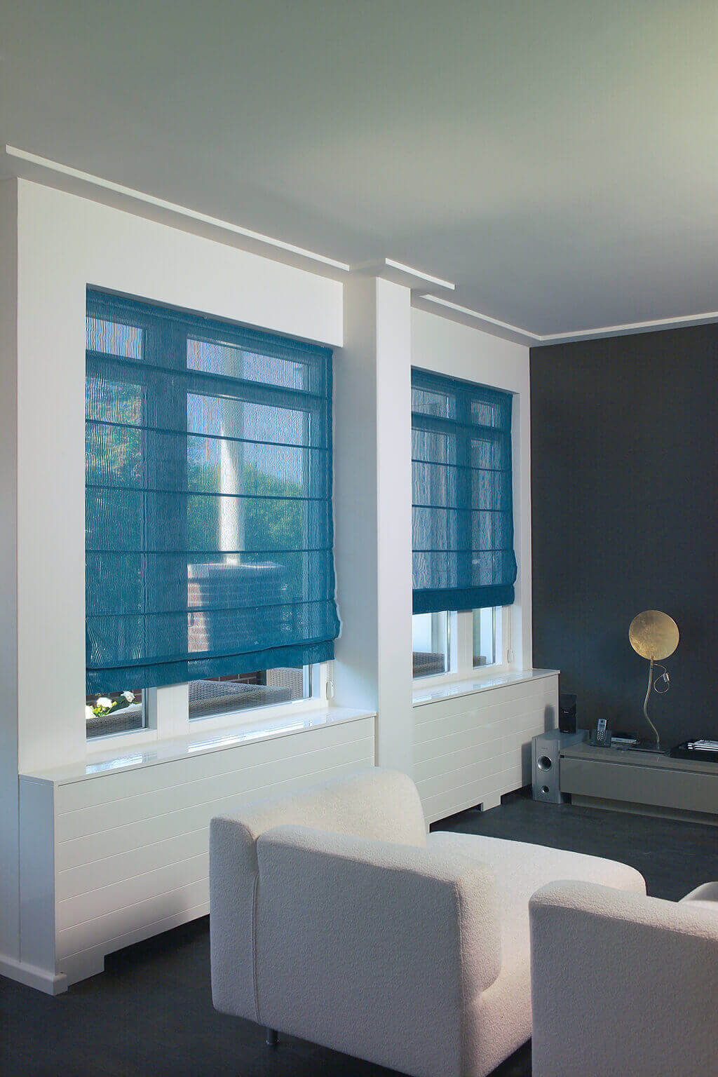 Blaues, lichtdurchlässiges Faltrollo an Fenstern im Wohnzimmer mit Blick auf die Terrasse