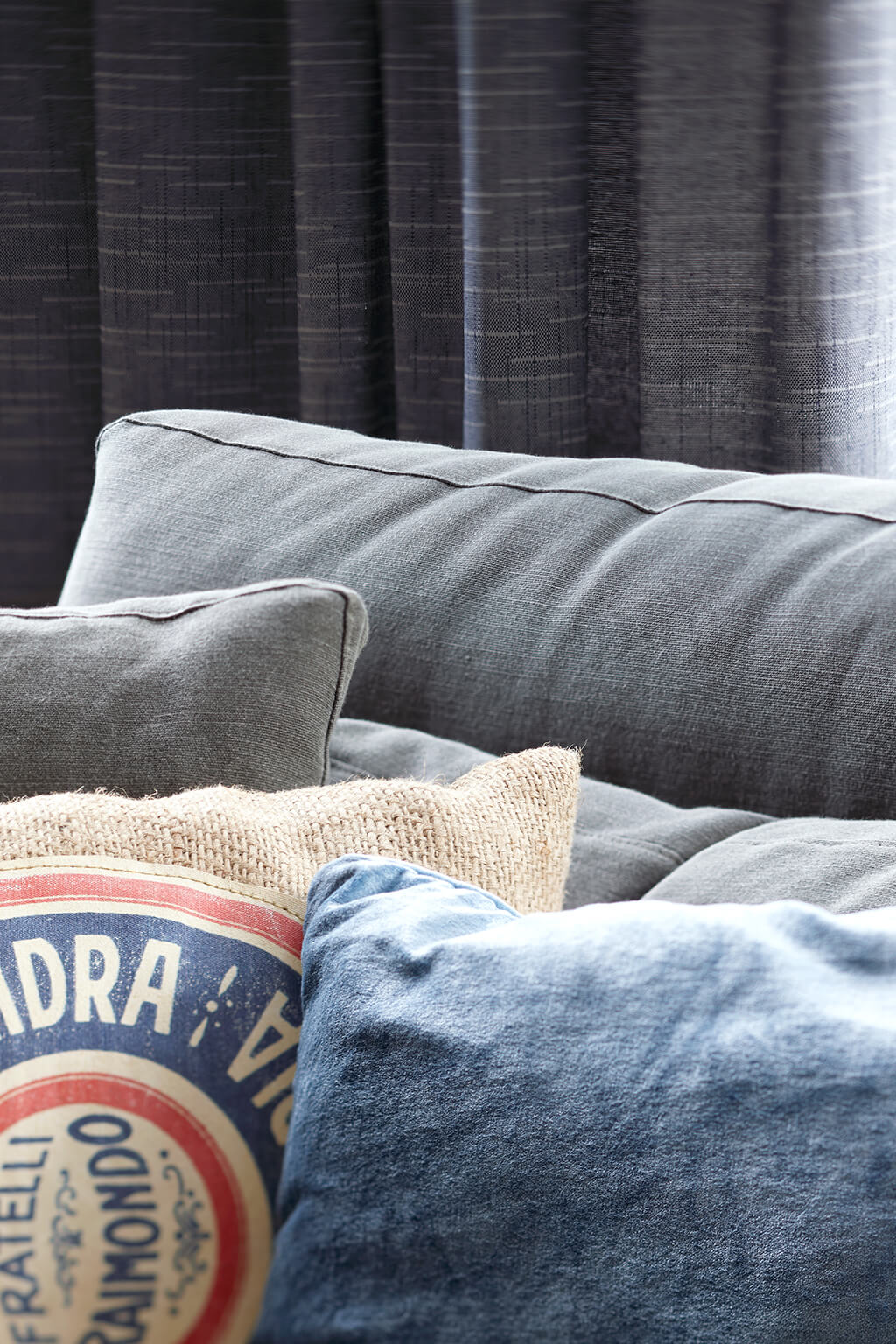 Detailaufnahme von einer grau-blauen Gardine hinter einer grauen Couch im Wohzimmer
