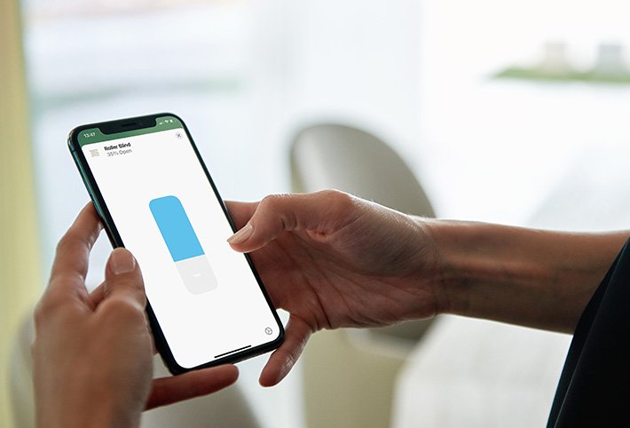 Frau benutzt die Apple Home App, um das Rollo zu öffnen/schließen.