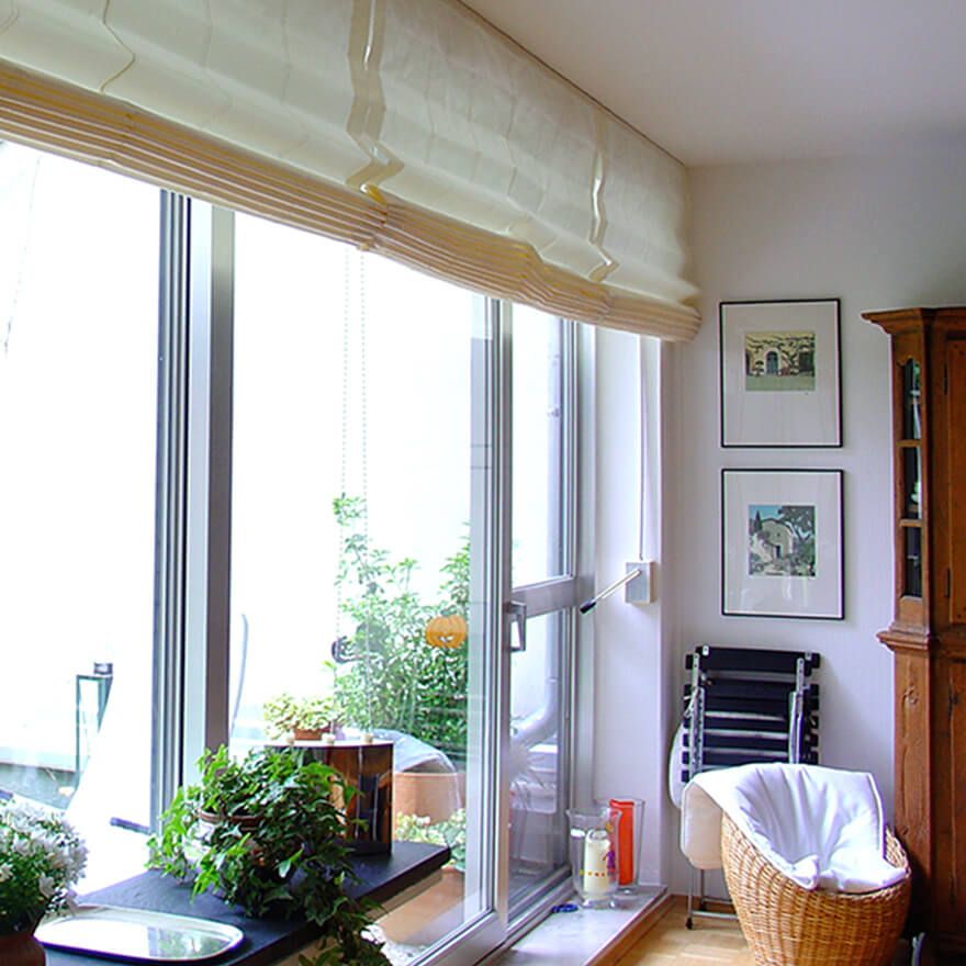 Cremefarbenes Raffrollo vor einer Fensterfront mit Balkontür Raffrollo cremefarben, Balkontür