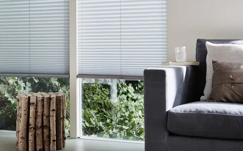 Weiße Plissees im Wohnzimmer mit grauem Sofa